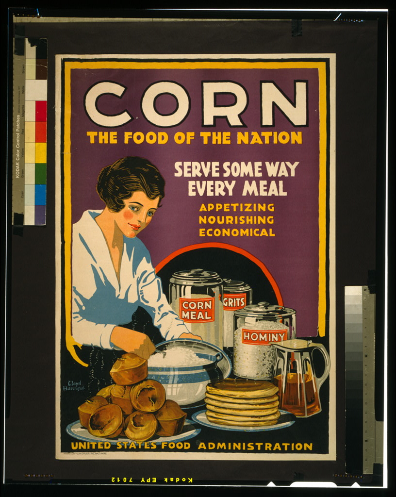 A woman serving a dish on a table covered with corn products. Caption: Corn, The Food of the Nation, Serve Some Way Every Meal, Appetizing, Nourishing, Economical"